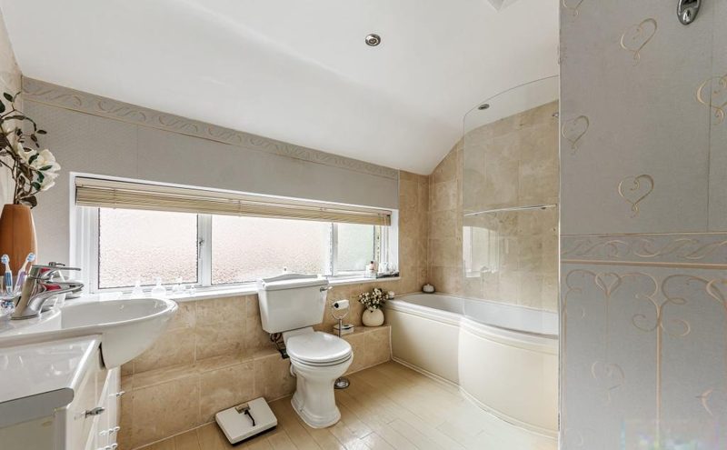 A family bathroom with a bath, WC, basin and a wide window.