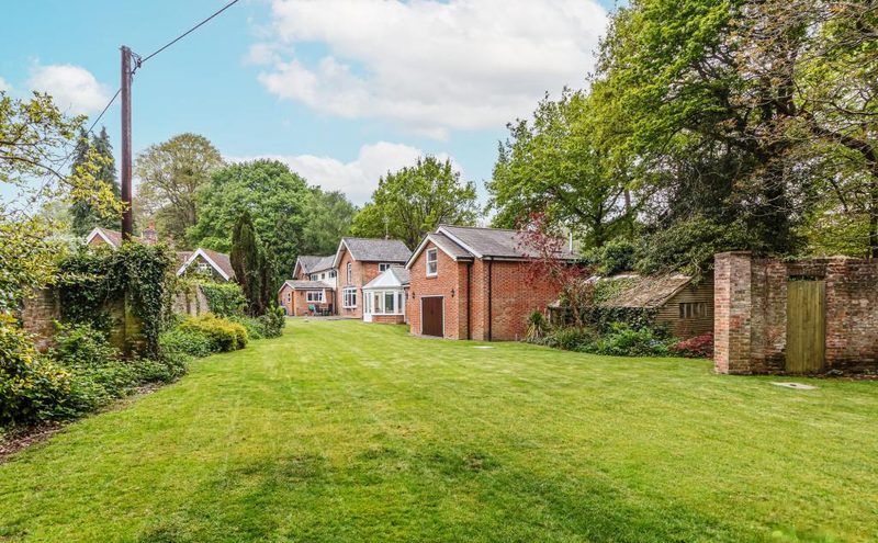 A large lawn with the house and outbuildings at the far end, framed by old brick walls.